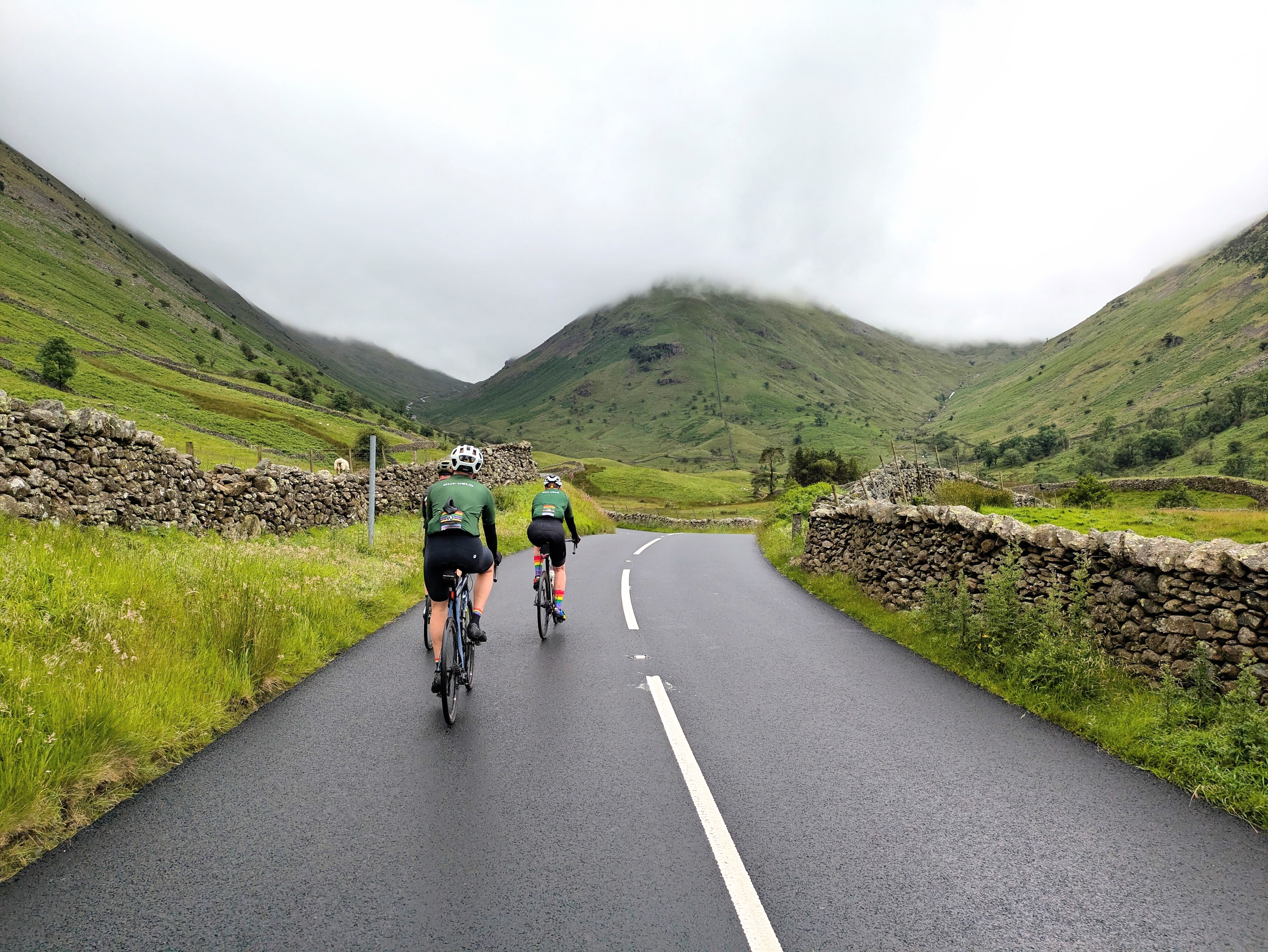 Two Out Velo riders climbing a quiet road through the Kirkstone Pass in the Lake District